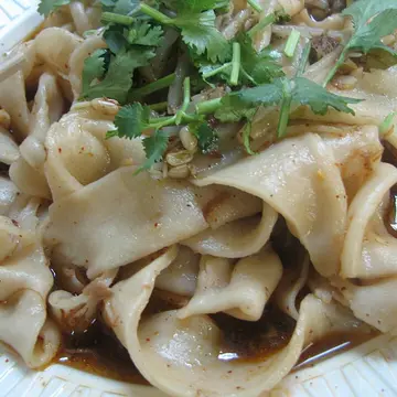 Very wide, flat hand-pulled noodles with herbs and a glossy sauce.