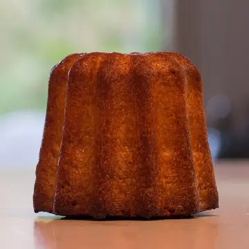 A small, dark, fluted cake with a glossy caramelised crust.