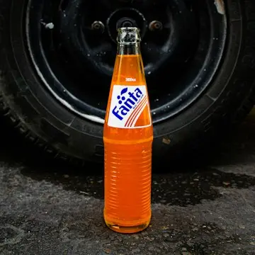 A glass bottle of bright orange soda.