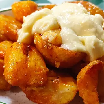 Chunks of fried potato under spicy red sauce and garlic mayonnaise.