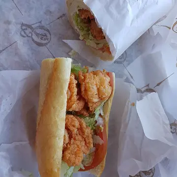 A long French bread sandwich stuffed with fried shrimp and lettuce.