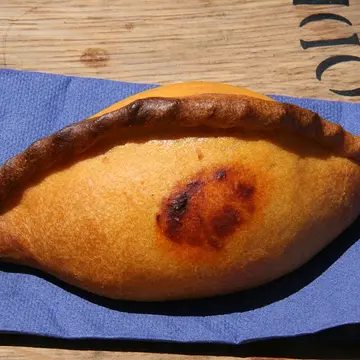 A golden baked pasty with a braided edge, plump with filling.