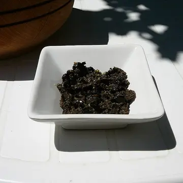 A small white dish of dark, chunky olive paste.