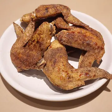 A plate of crispy fried chicken wings with a peppery glaze.